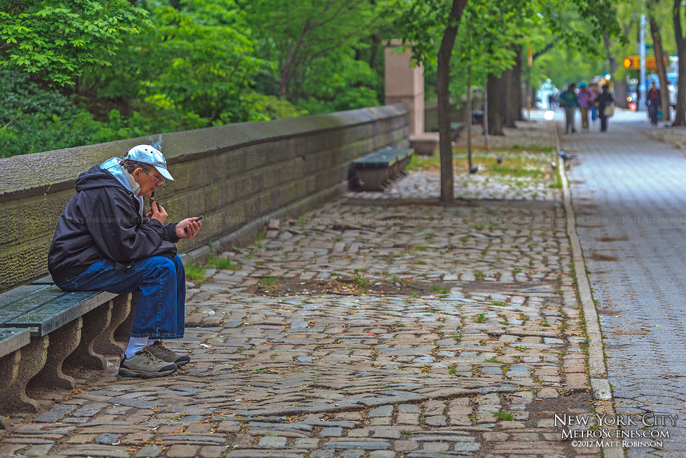 A man checks his cell phone while smoking a pipe